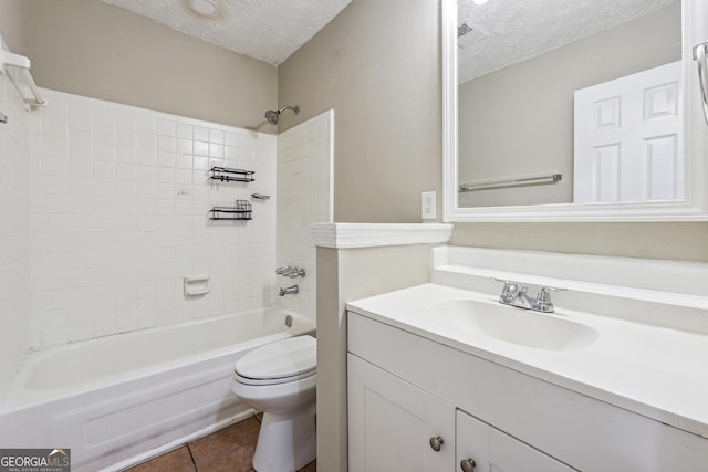 full bathroom featuring vanity, tile patterned floors, tiled shower / bath, toilet, and a textured ceiling