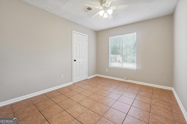 empty room with ceiling fan, light tile patterned floors, and a textured ceiling