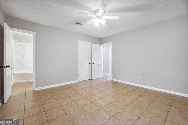 unfurnished bedroom with light tile patterned floors, a textured ceiling, and ceiling fan