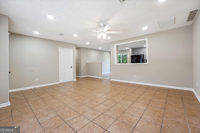 tiled empty room with ceiling fan and a textured ceiling