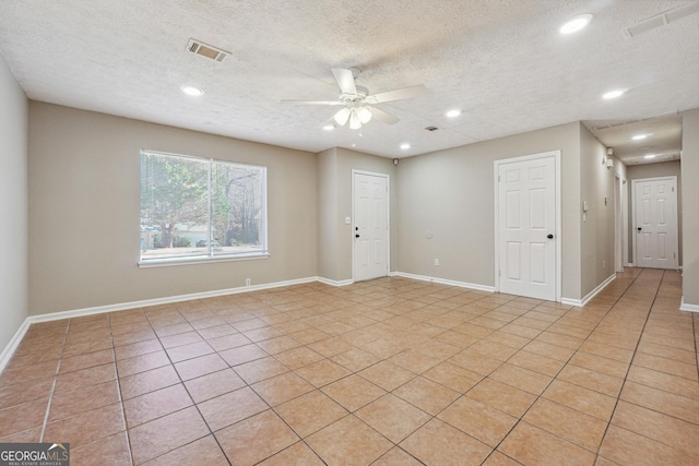 tiled spare room featuring a textured ceiling and ceiling fan