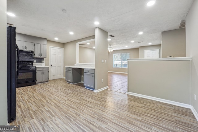 kitchen featuring a textured ceiling, gray cabinets, light hardwood / wood-style floors, and black appliances