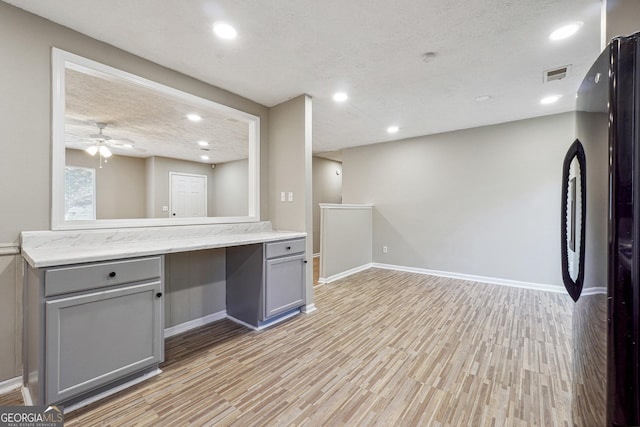 kitchen with gray cabinetry, ceiling fan, black refrigerator, and light wood-type flooring