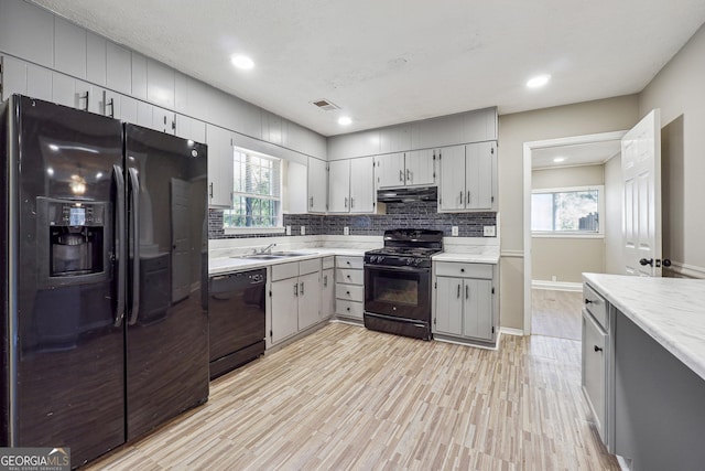 kitchen featuring black appliances, gray cabinets, sink, and light hardwood / wood-style flooring