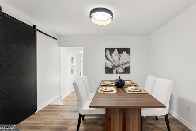 dining room with a barn door and hardwood / wood-style floors