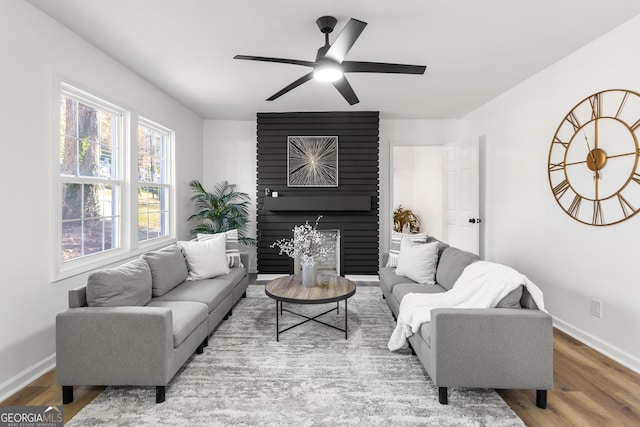 living room with a fireplace, wood-type flooring, and ceiling fan