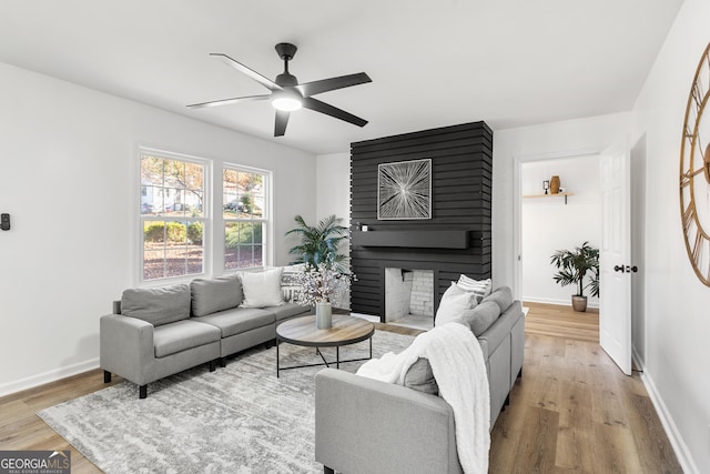 living room with ceiling fan, a fireplace, and light hardwood / wood-style flooring