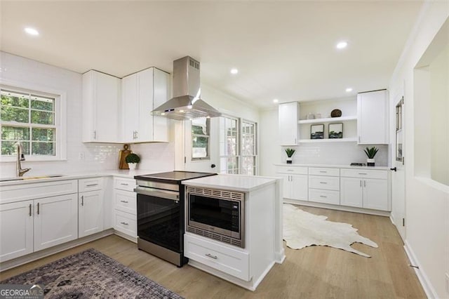 kitchen with open shelves, light countertops, appliances with stainless steel finishes, a sink, and exhaust hood