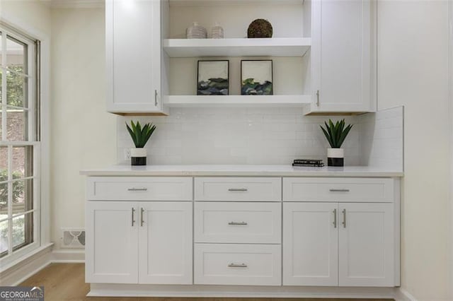 bar featuring light wood-type flooring, visible vents, baseboards, and backsplash