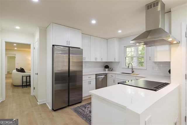 kitchen featuring stainless steel appliances, light countertops, white cabinetry, a sink, and island range hood