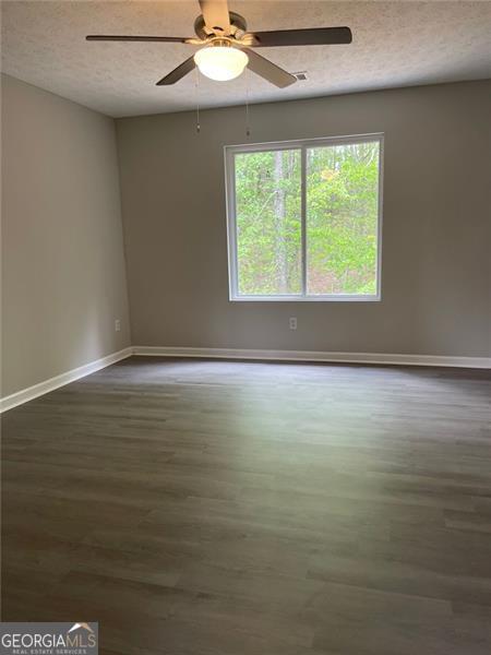 spare room with dark hardwood / wood-style floors, ceiling fan, and a textured ceiling