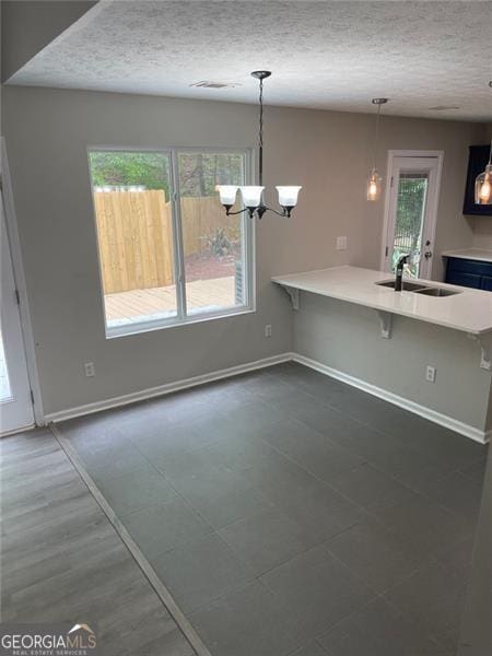 kitchen with kitchen peninsula, a breakfast bar, decorative light fixtures, and sink