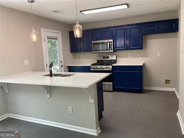 kitchen featuring appliances with stainless steel finishes, a breakfast bar, blue cabinets, sink, and hanging light fixtures