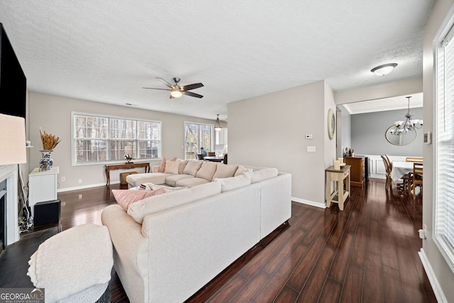 living room with ceiling fan with notable chandelier, a textured ceiling, and dark hardwood / wood-style flooring