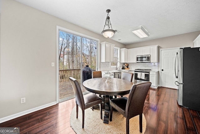 dining room with a textured ceiling, sink, and dark hardwood / wood-style floors