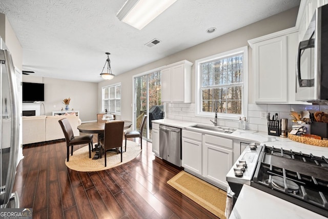 kitchen with sink, hanging light fixtures, dark hardwood / wood-style floors, white cabinets, and appliances with stainless steel finishes