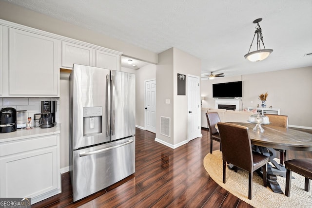 interior space featuring stainless steel fridge, dark hardwood / wood-style flooring, white cabinets, and pendant lighting