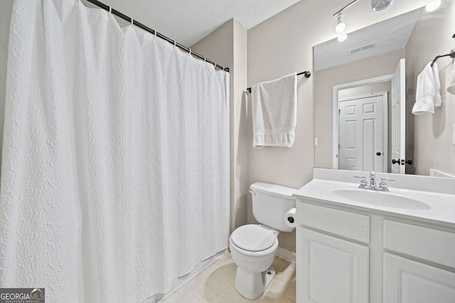 bathroom with vanity, toilet, and a textured ceiling