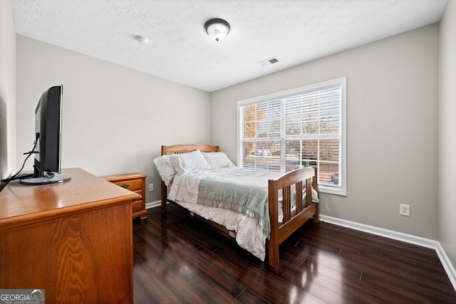 bedroom with a textured ceiling and dark wood-type flooring