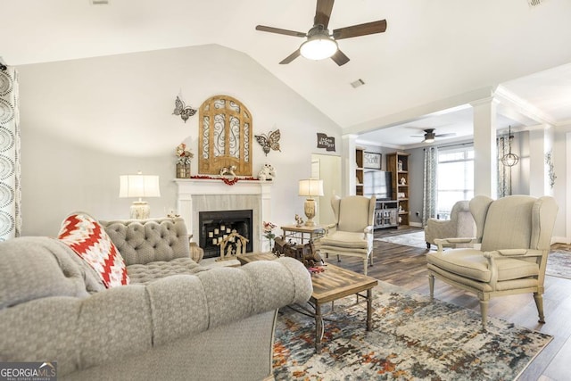 living room with hardwood / wood-style flooring, vaulted ceiling, ceiling fan, and a tiled fireplace