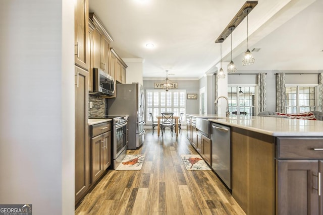 kitchen with decorative light fixtures, dark hardwood / wood-style flooring, stainless steel appliances, and an island with sink