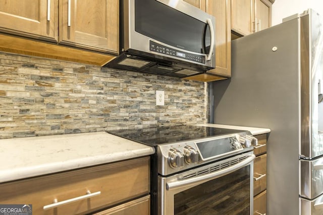 kitchen with appliances with stainless steel finishes, tasteful backsplash, and light stone counters