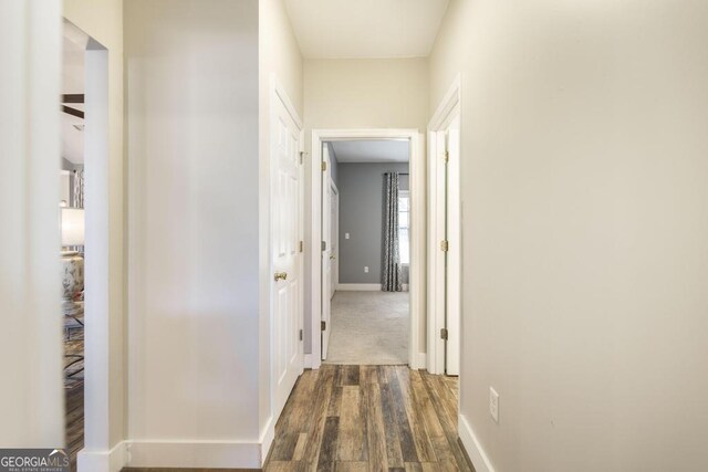 hallway featuring dark wood-type flooring and baseboards