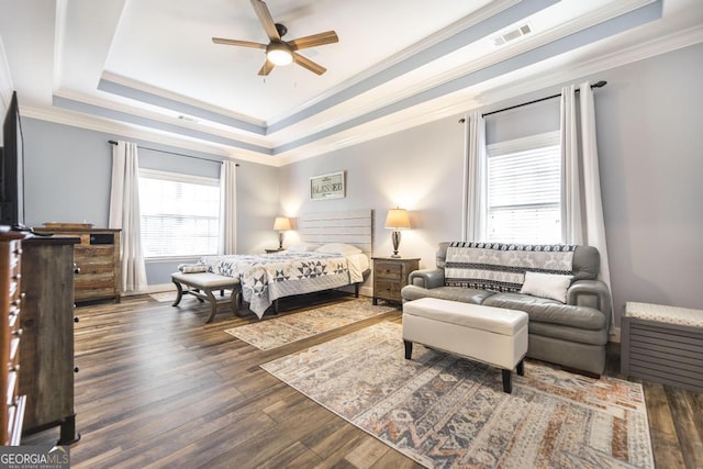 bedroom with dark hardwood / wood-style flooring, a tray ceiling, ceiling fan, and ornamental molding