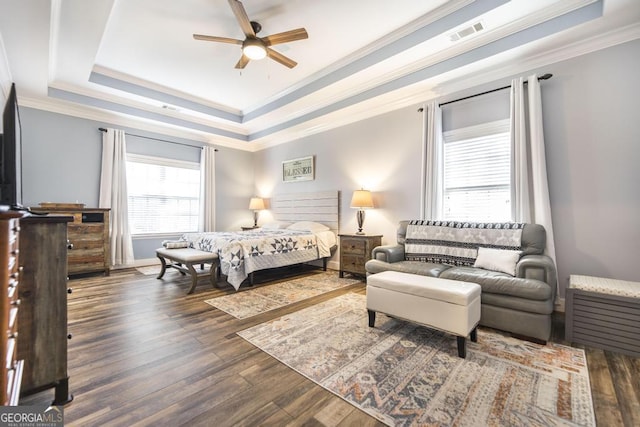 bedroom featuring a raised ceiling, wood finished floors, ornamental molding, a ceiling fan, and baseboards