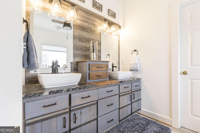 full bath with double vanity, baseboards, and wood finished floors