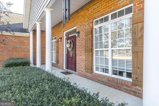 property entrance featuring brick siding and a shingled roof