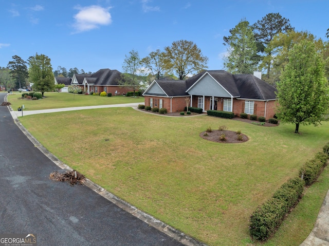 view of front of property featuring brick siding, a front lawn, and driveway