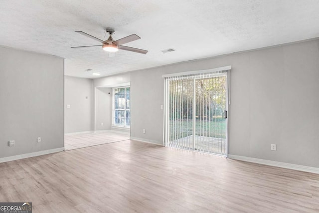 spare room with a wealth of natural light, a textured ceiling, and light wood-type flooring