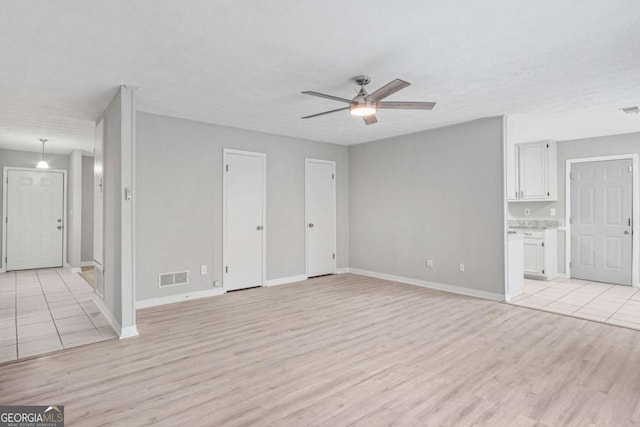 unfurnished living room with ceiling fan, light wood-type flooring, and a textured ceiling