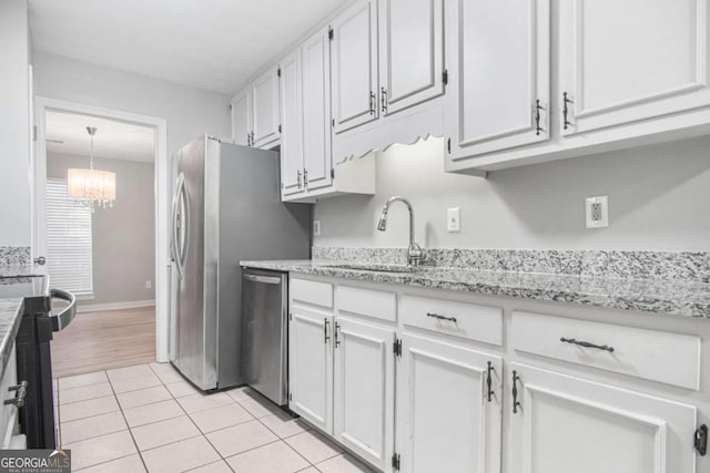 kitchen with sink, stainless steel dishwasher, a notable chandelier, light tile patterned flooring, and white cabinetry