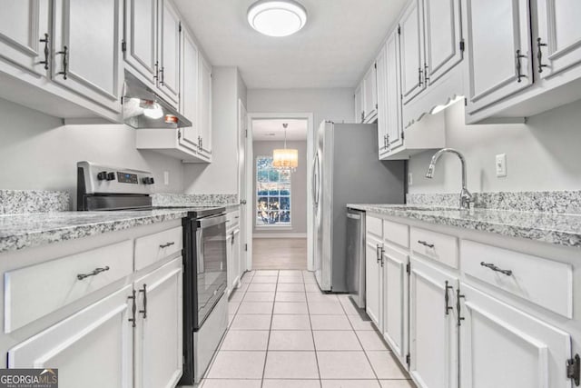 kitchen with white cabinets, light tile patterned floors, stainless steel appliances, and light stone counters