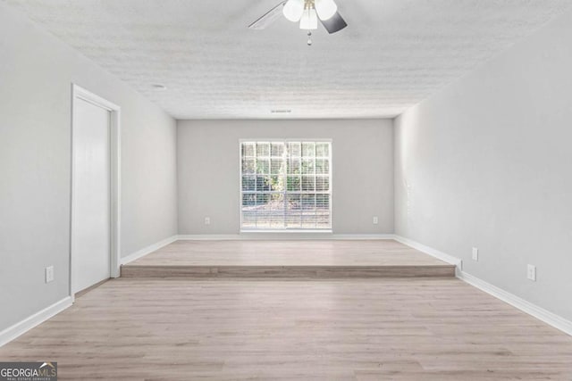 spare room with a textured ceiling, light hardwood / wood-style floors, and ceiling fan