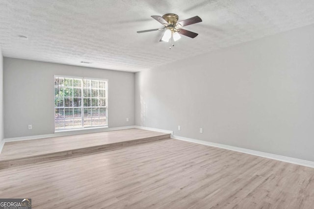 spare room featuring ceiling fan, light hardwood / wood-style floors, and a textured ceiling