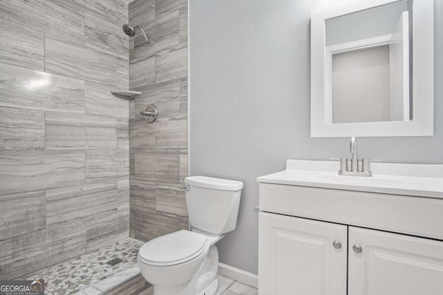 bathroom featuring vanity, toilet, and a tile shower