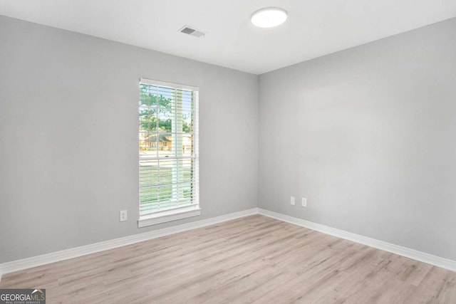 empty room with plenty of natural light and light hardwood / wood-style flooring