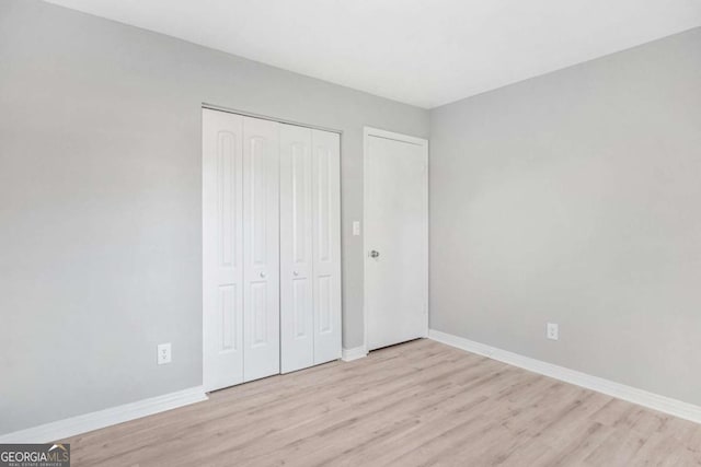 unfurnished bedroom featuring light wood-type flooring and a closet