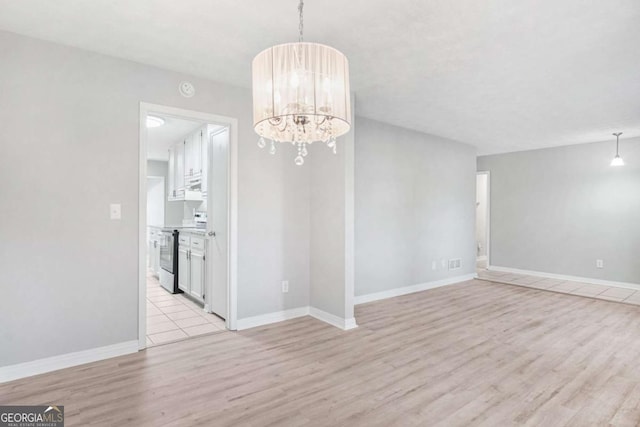 unfurnished dining area with light hardwood / wood-style flooring and a notable chandelier