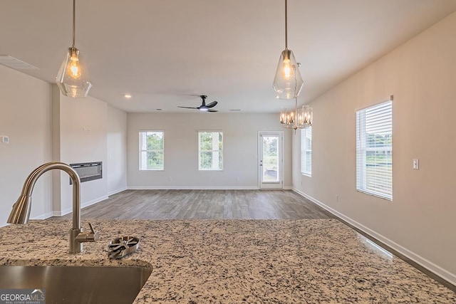 unfurnished living room featuring ceiling fan with notable chandelier, dark hardwood / wood-style flooring, and sink