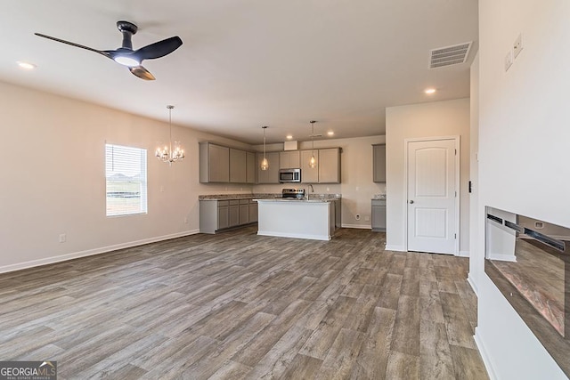 kitchen with gray cabinets, ceiling fan with notable chandelier, wood-type flooring, and decorative light fixtures