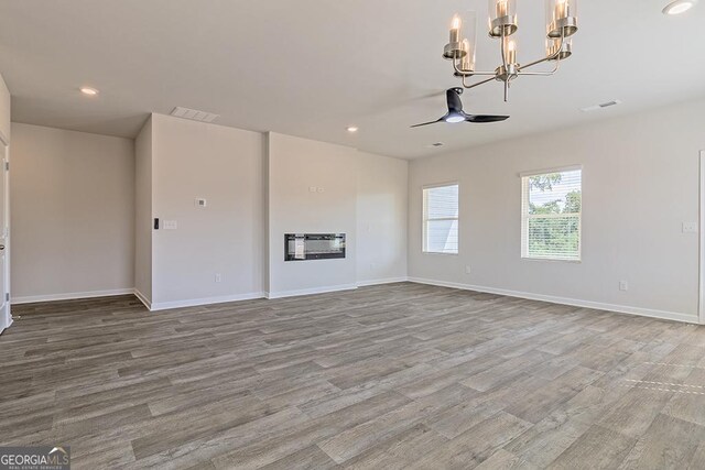 unfurnished living room with light hardwood / wood-style flooring and ceiling fan with notable chandelier