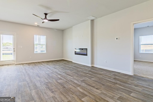 unfurnished living room with hardwood / wood-style flooring, ceiling fan, and a wealth of natural light