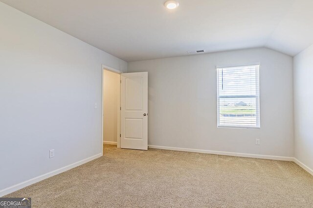 carpeted empty room with lofted ceiling