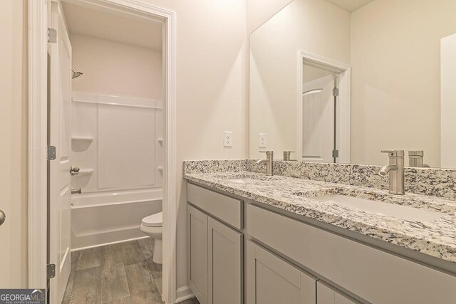 full bathroom featuring washtub / shower combination, wood-type flooring, vanity, and toilet