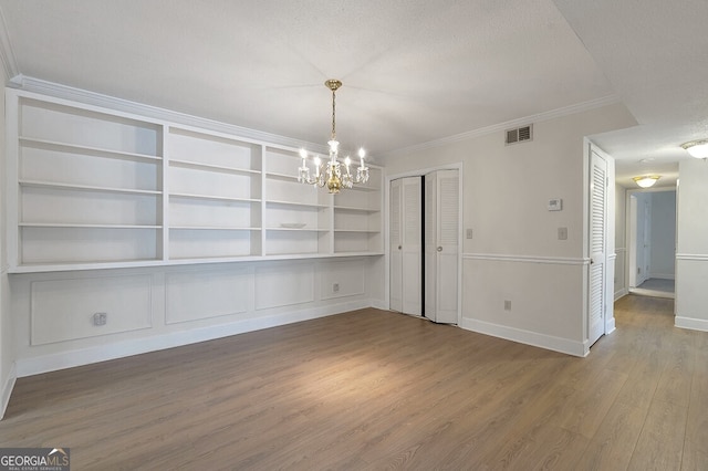 6851 Roswell Rd Unit D14, Atlanta, GA 30328 - unfurnished dining area with a chandelier, wood finished floors, ornamental molding, built in shelves, and a textured ceiling