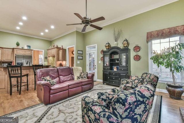 living room with light wood-type flooring, ceiling fan, and ornamental molding